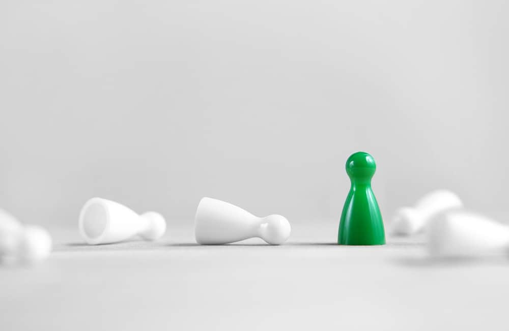 a green pawn standing in front of a group of white pawns